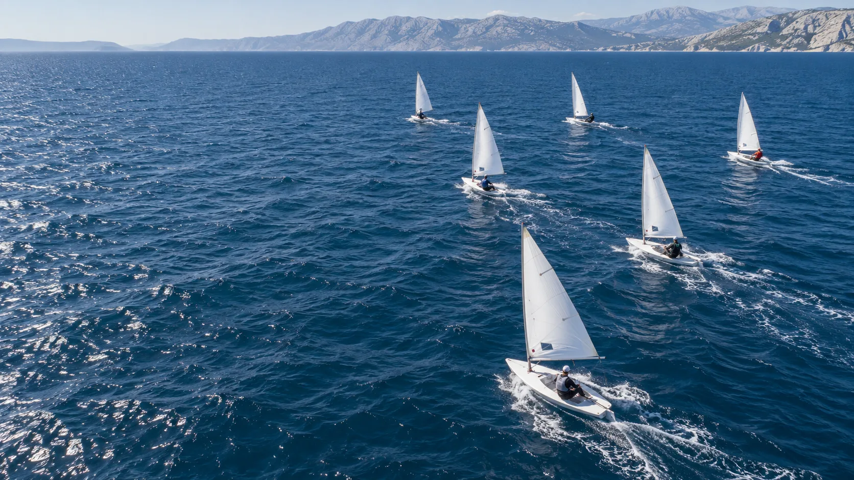 Illustrative aerial scene of dinghies racing across blue water